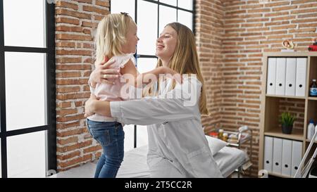 Le médecin pédiatre partage un câlin réconfortant avec un patient enfant heureux à l'intérieur de la clinique, des sourires radieux confiants dans les soins de santé Banque D'Images