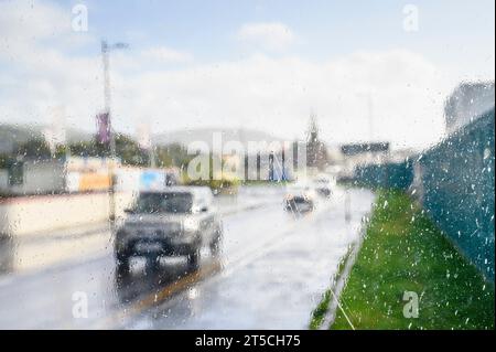 Vue floue regardant à travers une fenêtre d'abri à des voitures conduisant sous une douche de pluie, Royaume-Uni Banque D'Images