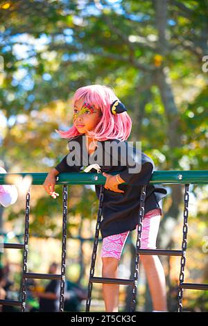 Halloweenpalooza - Dennis, Massachusetts sur Cape Cod. Une fête familiale d'Halloween. Une fille aux cheveux magenta sur la jungle gym Banque D'Images