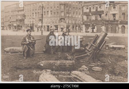 «Berliner straßenkämpfe, März 1919. Schwere Minenwerfer' / 'Berlin Street Fighting, mars 1919. Mortiers lourds ». Quatre soldats allemands sur une zone gazonnée près d'une rue berlinoise, trois ont des fusils, un est en train de faire fonctionner un gros mortier. Les coquillages sont sur l'herbe autour d'eux, dans des couvertures en osier. La photographie montre des combats de rue pendant les batailles du 1919 mars à Berlin Banque D'Images