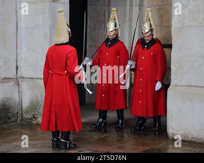 Soldats du sauveteur du roi à la relève de la garde dans leurs uniformes de cérémonie portant de longs manteaux pour la période froide de l'année à Whitehall, Londres, Royaume-Uni Banque D'Images