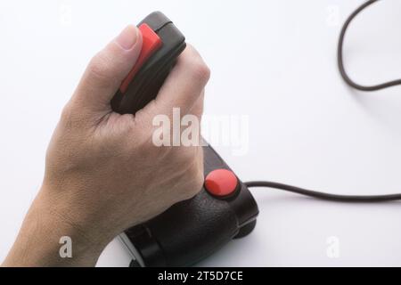 Un homme jouant à un jeu vidéo avec un joystick rétro. Joystick de jeu du milieu des années 1980 Banque D'Images