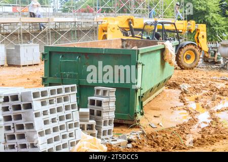 Une benne vide pour débris de déchets de construction à proximité du chantier est chargée de débris Banque D'Images