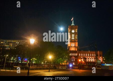 Incroyable tour de l'horloge de l'Hôtel de ville de Berlin ( Rotes Rathaus) et pleine lune derrière. Personnes en mouvement flou. Drapeau du Land de Brandebourg (ou Berlin ?) Banque D'Images