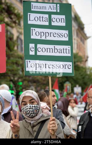 Rome, Italie. 4 novembre 2023. Une femme avec le hijab agite la victoire et brandit un signe avec les paroles de l'Imam Ali (quatrième calife orthodoxe, cousin et gendre de Muhammad, parmi les premiers convertis à l'Islam) ''lutte avec les opprimés et lutte contre l'oppresseur'' lors de la marche pro-palestinienne à Rome. Environ 5 000 personnes ont pris part à la marche romaine en soutien à la Palestine, comme un sit-in contre le jour des forces armées et organisé par des mouvements étudiants, des centres sociaux et certains mouvements et comités de gauche dans d'autres villes, telles que Gênes et Pise. Crédit : ZUMA Press, Inc./Alamy Live Nouveau Banque D'Images