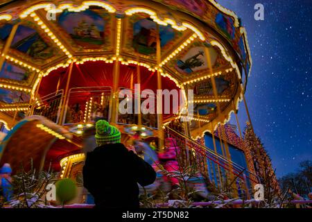 Carrousel coloré sur la foire de Noël la nuit. Nouvel an et vacances de Noël en Europe. Mise au point sélective, flou de mouvement. Banque D'Images