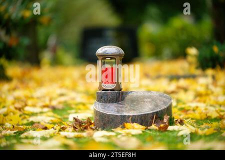 lanterne grave sur une pierre tombale d'urne dans un pré couvert de feuilles d'automne Banque D'Images