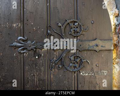 Gros plan d'une porte médiévale en bois avec des éléments en acier forgé. Le design décoratif antique a des formes d'ornement et appartient à un vieux château. Banque D'Images