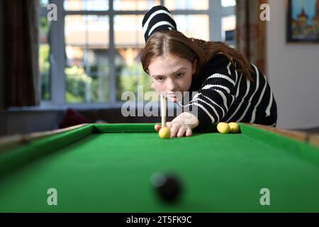 Adolescente jouant au jeu traditionnel de pub de bagatelle dans le salon à la maison Banque D'Images