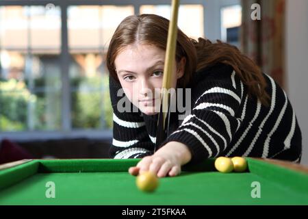 Adolescente jouant au jeu traditionnel de pub de bagatelle dans le salon à la maison Banque D'Images