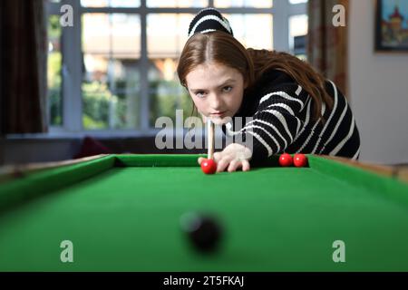 Adolescente jouant au jeu traditionnel de pub de bagatelle dans le salon à la maison Banque D'Images