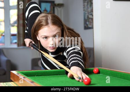 Adolescente jouant au jeu traditionnel de pub de bagatelle dans le salon à la maison Banque D'Images