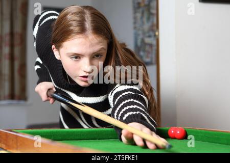 Adolescente jouant au jeu traditionnel de pub de bagatelle dans le salon à la maison Banque D'Images