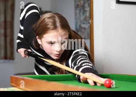 Adolescente jouant au jeu traditionnel de pub de bagatelle dans le salon à la maison Banque D'Images