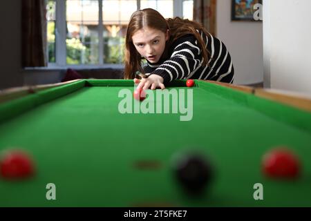 Adolescente jouant au jeu traditionnel de pub de bagatelle dans le salon à la maison Banque D'Images