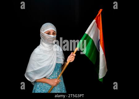 Jeune femme indienne tenant le drapeau national indien , drapeau de l'Inde, isolé sur fond noir Banque D'Images