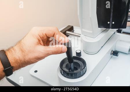 La main de l'homme tient la poignée de l'appareil. Dispositif ophtalmologique moderne. Banque D'Images