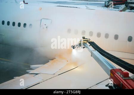 Dégivrage de l'aile d'avion avant le décollage. Hiver nuit glaciale et service au sol à l'aéroport. Banque D'Images