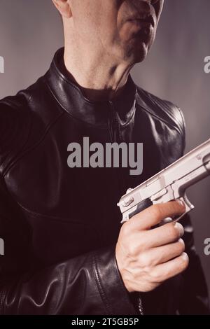 Veste en cuir noir hitman détective espion meurtrier assasin avec photo de portrait d'arme à feu. Banque D'Images
