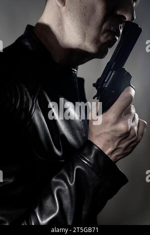 Veste en cuir noir hitman détective espion meurtrier assasin avec photo de portrait d'arme à feu. Banque D'Images