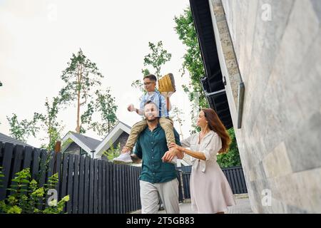 Papa porte un fils joyeux avec des gadgets de baseball sur ses épaules Banque D'Images