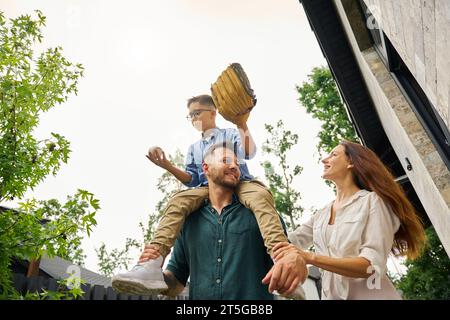 L'homme porte son fils avec des gadgets de baseball sur ses épaules Banque D'Images