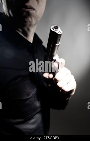 Mercenaire tueur espion assasin détective avec photo de studio de portrait d'arme à feu. Banque D'Images