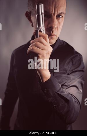 Mercenaire tueur espion assasin détective avec photo de studio de portrait d'arme à feu. Banque D'Images