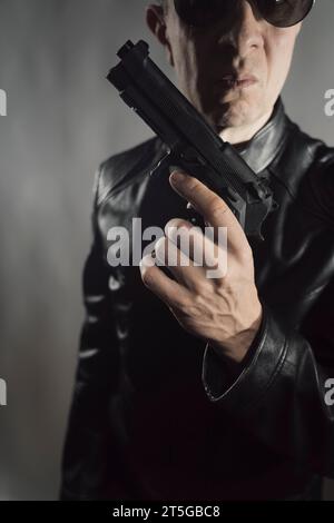 Veste en cuir noir hitman détective espion meurtrier assasin avec photo de portrait d'arme à feu. Banque D'Images