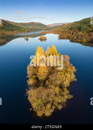 Aberfoyle, Stirling, Écosse, Royaume-Uni. 5 novembre 2023. Vue aérienne d'une petite île couverte d'arbres au milieu du Loch Chon dans les couleurs de la fin de l'automne à Banque D'Images