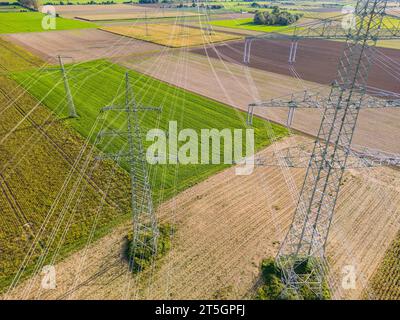 De nombreuses lignes électriques entre les poteaux électriques au-dessus d'un champ agricole comme un plan aérien Banque D'Images