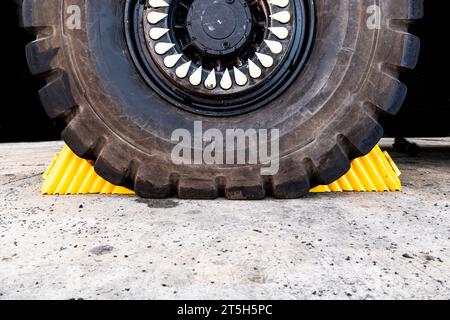 Une paire de cales de roue jaunes pour usage intensif calées contre un pneu de véhicule comme mesure de sécurité pour empêcher le véhicule de rouler avec un espace de copie Banque D'Images