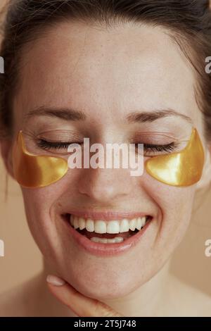 femme moderne heureuse avec des taches d'oeil sur fond beige. Banque D'Images