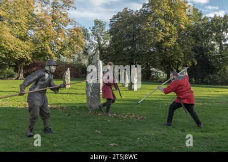 Llanrwst, pays de Galles, Royaume-Uni - 22 octobre 2023 - trois jeunes vêtus de tenues vintage se battant avec des lances dans un champ Banque D'Images