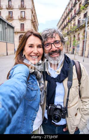 Selfie vertical souriant couple touristique caucasien mature posant en plein air. Des gens heureux amoureux des années soixante Banque D'Images