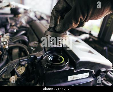 La main d'un mécanicien automobile ouvre le bouchon d'huile moteur pour inspecter avant de changer l'huile moteur de voiture concept d'entretien de voiture Banque D'Images