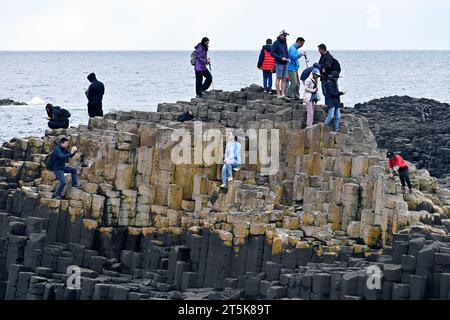 Touristes grimpant sur les rochers à la chaussée des géants de l'Irlande du Nord Banque D'Images