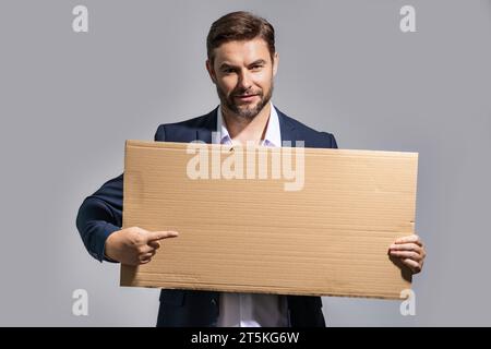 L'homme en costume tient une affiche avec un espace pour les copies. Étiquette prête pour les produits de l'espace de copie. Connectez-vous à votre espace de texte. Homme montrant un tableau vierge en studio Banque D'Images