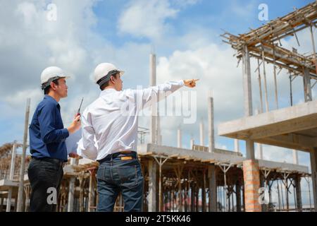 Deux ingénieurs travaillant et vérifiant le plan sur le chantier de construction. Banque D'Images