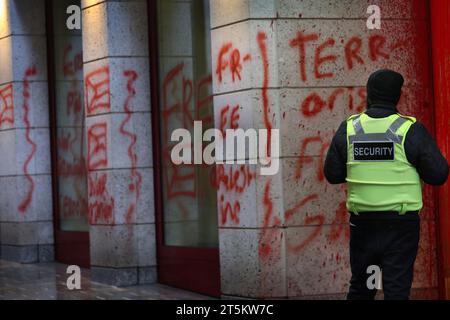 Un garde de sécurité se tient debout et regarde les graffitis pro-palestiniens à l’extérieur du bâtiment. Des militants de Palestine action occupent et ciblent le géant italien de l'industrie de l'armement Leonardo à leur siège à Londres et les ferment. Leonardo fournit à Israël des avions de combat et des armes qui sont actuellement utilisés à Gaza. Palestine action exige que les compagnies d’armement qui fournissent des armes à Israël ferment définitivement leurs portes. Ils ont annoncé que les entreprises vendant des armes aux Forces de défense israéliennes et à leurs partenaires seraient visées par une action directe. Ces actions sont destinées à Banque D'Images