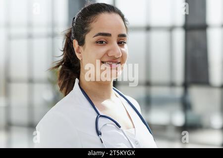 Femme dentiste debout avec les bras croisés. Dentiste confiant debout dans un couloir d'hôpital dans un manteau blanc. Banque D'Images