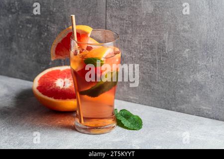 Thé glacé avec glace, menthe et pamplemousse. Une boisson rafraîchissante froide avec des ingrédients sur fond gris. Copier l'espace. Banque D'Images