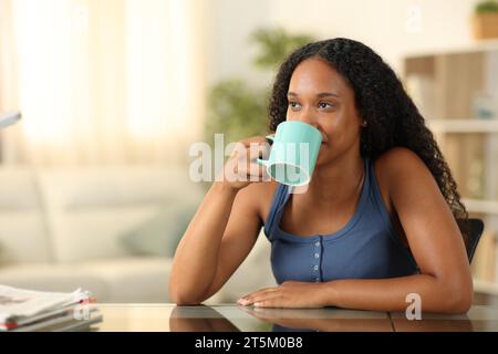 Femme noire buvant du café assise à la maison Banque D'Images