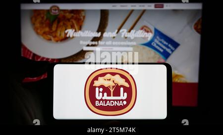 Personne tenant un smartphone avec le logo de la compagnie laitière et alimentaire qatarie Baladna devant le site Web. Concentrez-vous sur l'affichage du téléphone. Banque D'Images