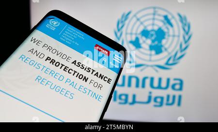 Téléphone portable avec le site Web de l'agence des Nations Unies pour les réfugiés Plalestine UNRWA devant le logo. Effectuez le focus sur le coin supérieur gauche de l'écran du téléphone. Banque D'Images