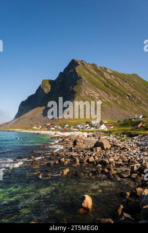 Village côtier de Vikten dans les Lofoten, Norvège, par une journée claire et ensoleillée, montagne en arrière-plan. Rochers et pierres et mer turquoise. Banque D'Images