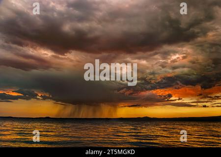 Coucher de soleil rouge avec nuages spectaculaires et colonne de pluie sur le lac Bolsena. Bolsena, province de Viterbo, Latium, Italie, Europe Banque D'Images