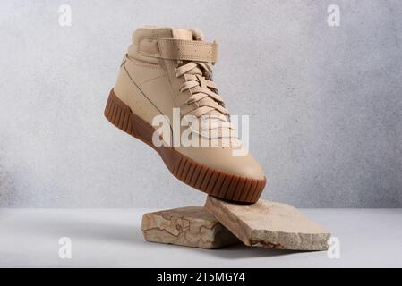 Bottes décontractées en cuir beige sur fond gris. Ñreative photographie pour une affiche publicitaire pour des publicités de chaussures Banque D'Images