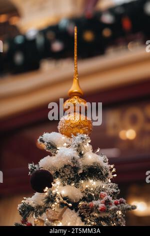 Détails magiques confortables, lumières bokeh, fond doré festif. Sapin de Noël décoré de neige, guirlandes et étoile dorée. Banque D'Images