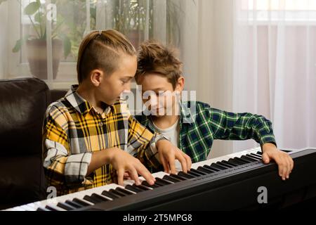 Deux garçons en chemises à carreaux profitant d'une leçon de piano ensemble dans une salle confortable Banque D'Images